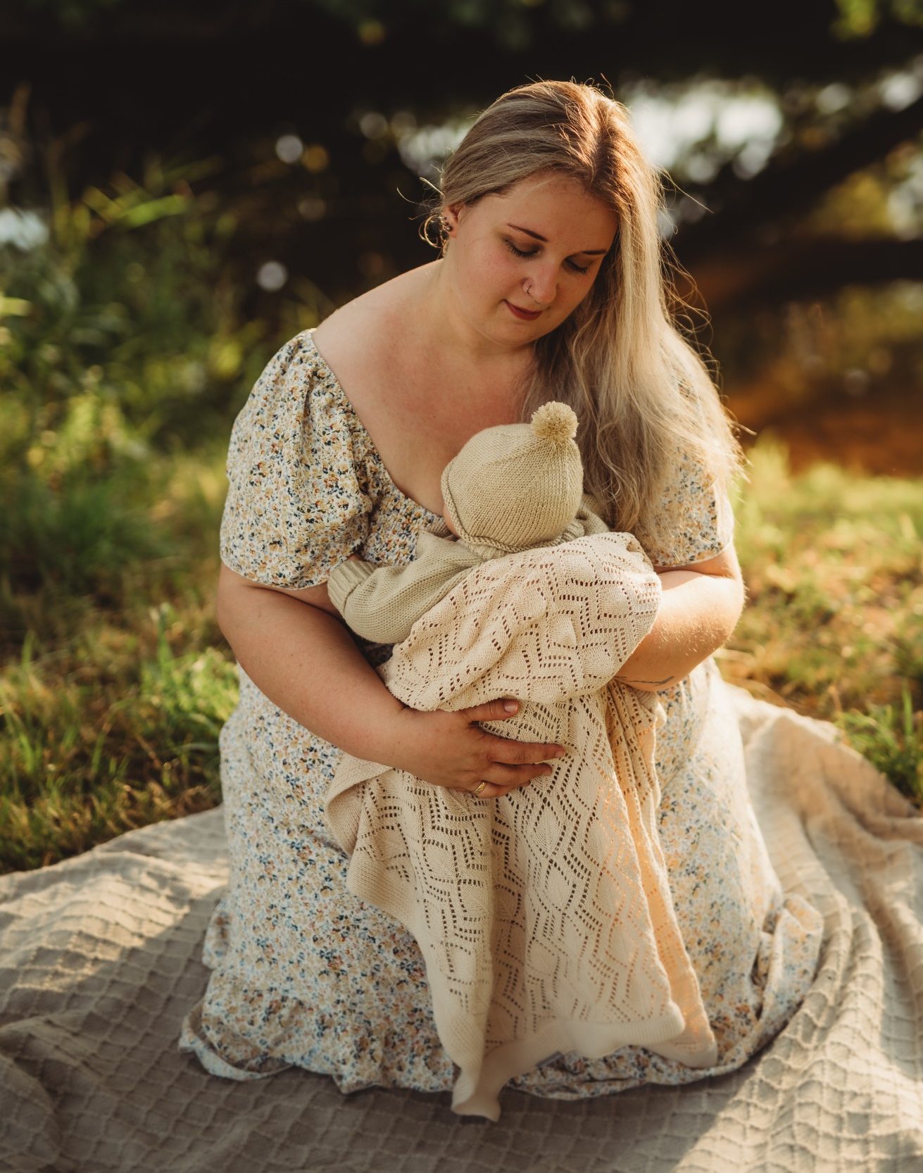 Frau mit langen Haaren hält ein Kind in einem natrurbelassenen Umfeld.
